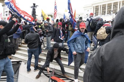 Los manifestantes derribando las vallas que rodeaban el Capitolio antes de irrumpir en él.