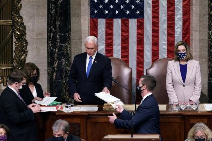 Pence da lectura en el Capitolio al acta que confirma a Biden como presidente junto a Nancy Pelosi.