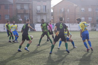 Un àrbitre, al fons, dirigint un partit del futbol lleidatà.