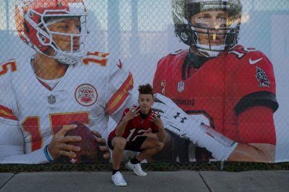 Un aficionat, al costat del cartell promocional de la Super Bowl.