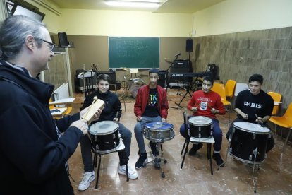 Cuatro alumnos siguiendo las instrucciones del profesor en una sesión de musicoterapia.