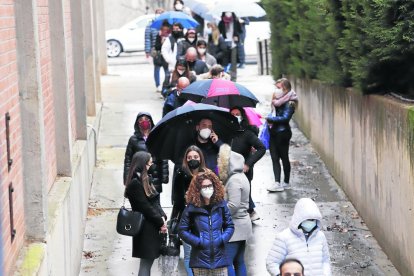 La farmacéutica Sílvia Pallàs recibe la vacuna y a la derecha, colas ante el pabellón Onze de Setembre.