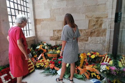 Dos mujeres contemplan las flores de las ofrendas en el Roser.