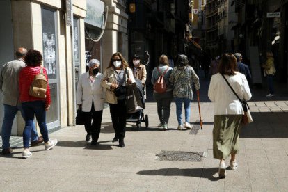 Gente paseando por|para el Eje Comercial de Lérida con mascarilla.