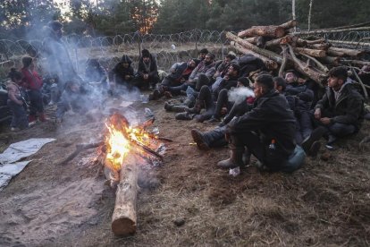 Un grupo de migrantes espera alrededor de una hoguera una oportunidad para cruzar a Polonia.