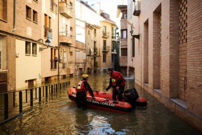 Dos bomberos navegan por una de las calles anegadas de Tudela. 