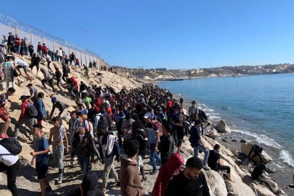 Un grup de persones proven de creuar la tanca fronterera que separa Fnideq (Castillejos, Marroc) i Ceuta aquest dimecres.