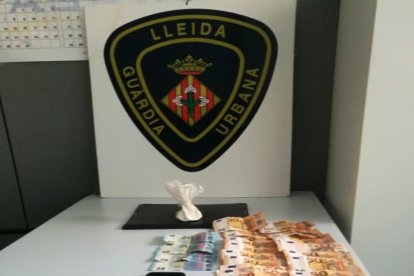 La cocaïna i els bitllets localitzats per la Guàrdia Urbana de Lleida a l'interior d'un vehicle.