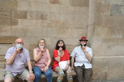 Veïns de Lleida fent el posat de treure’s la mascareta al banc del ‘si no fos’ de la Paeria.