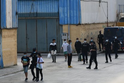 Agentes de la Policía de Ceuta acompañan a menores a las naves habilitadas para su acogida.