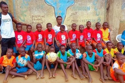 Un grupo de niños marfileños, con sus técnicos, posan con ropa y balones llegados desde Mollerussa. 