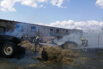 Els Bombers sufocant l’incendi a les bales de palla.