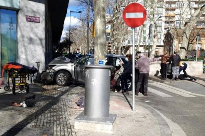 El vehículo tras chocar con un edificio y los servicios de emergencias atendiendo a un herido.