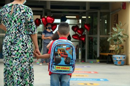 Imagen de un niño llegando a clase de la mano de su madre.