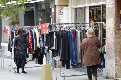 Dos mujeres ante la parada de uno de los comercios que participa en la iniciativa “Rebaixes al carrer”. 