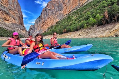 A la izquierda, varios jóvenes en caiac por el Congost de Montrebei y a la derecha, la vuelta de turismos tras el fin de semana en la rotonda de Margalef . 