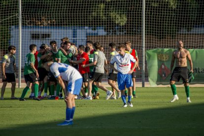 Adrià Fernández, sense samarreta, celebra amb els seus companys de l’Ascó l’ascens mentre en primer pla dos jugadors del Mollerussa mostren el seu abatiment.