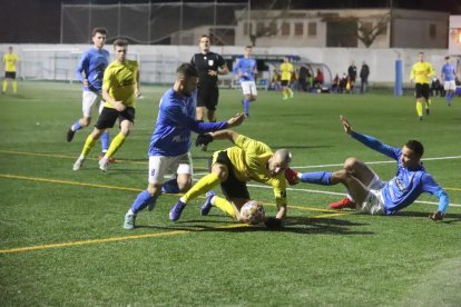 Adrià Fernández lucha un balón ante dos jugadores del Alcarràs.