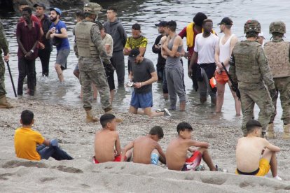 Menores sentados en la playa tras arribar a Ceuta la semana pasada.