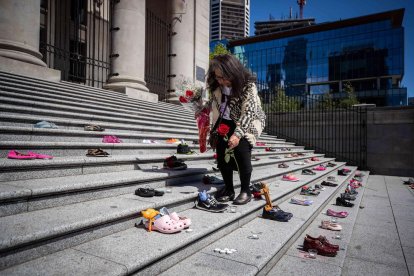 Una nadiua col·loca roses en homenatge als 215 nens les restes dels quals s’han trobat aquests dies.