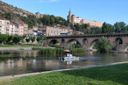 La embarcación que limpia de algas el cauce del río en Balaguer.