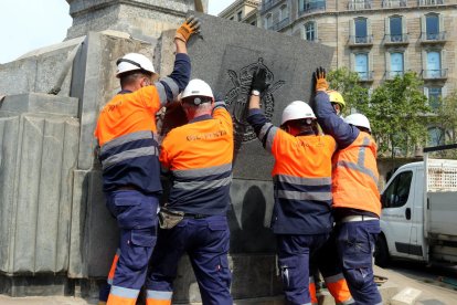 Operarios del ayuntamiento de Barcelona quitando el escudo, ayer.