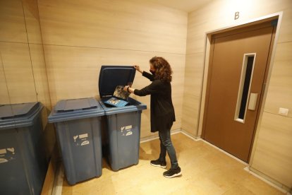 Una veïna diposita paper als contenidors del seu bloc.