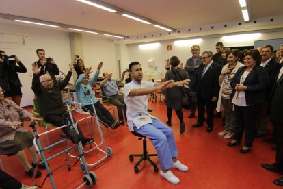 Usuarios de la nueva residencia hacen gimnasia ante las autoridades en la sala de fisioterapia.