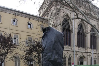 La estatua, tapada, y a la izquierda, durante su restauración.