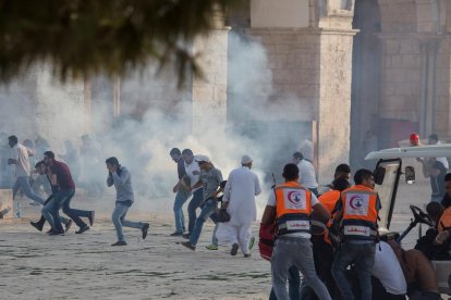 Palestinos se ponen a cubierto durante los enfrentamientos con la policía antidisturbios israelí.