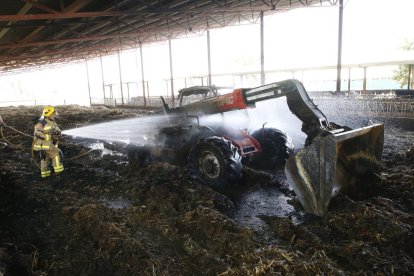 Un bomber llança aigua sobre la màquina que va quedar calcinada a Vallfogona de Balaguer.