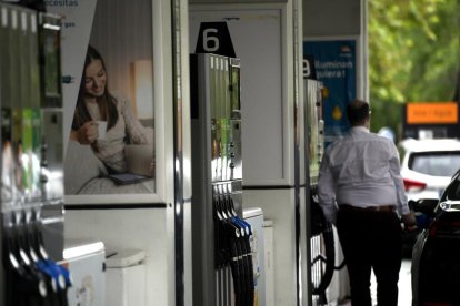 Varios surtidores de combustible y un hombre repostando.