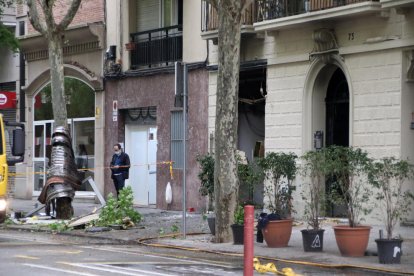 El carrer València, a l'altura del número 73, amb el local del costat afectat per l'explosió i la persiana cargolada a l'arbre