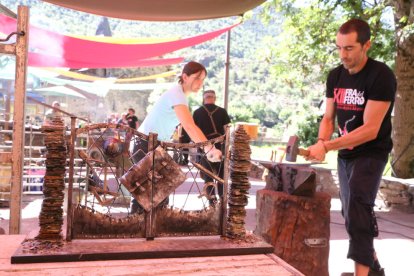 Herreros trabajando ayer durante la Fira del Ferro y la maqueta de la puerta que crearán.