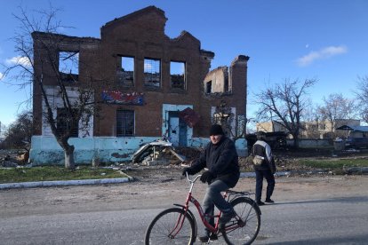 Un hombre en bicicleta circula por la devastada aldea ucraniana de Yatskivka.