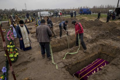 Diverses persones enterren un cos al cementiri de Butxa, a prop de Kíiv.