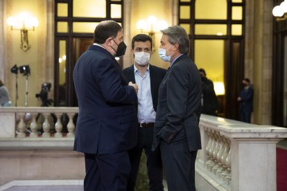 El expresidente Artur Mas y el exvicepresidente Oriol Junqueras, acompañado de un colaborador, charlan antes de la investidura del presidente de la Generalitat, Pere Aragonès, el 21 de mayo de 2021.