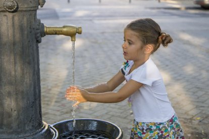 Una nena refrescant-se en una font el mes d’agost passat.