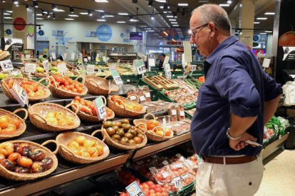 Un hombre observa los precios de los tomates en un supermercado. 