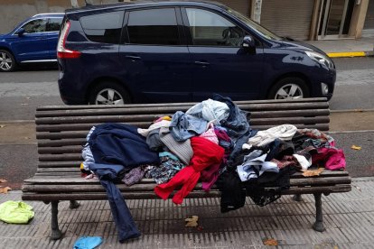 Ropa tirada en un banco al lado de un contenedor en La Bordeta