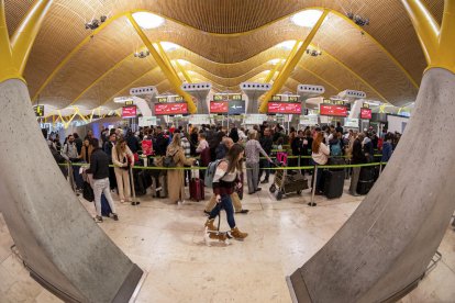 Passatgers preparant-se per embarcar a Barajas dissabte.