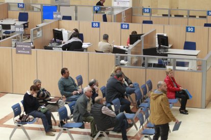 Imagen interior de una oficina de la Agencia Tributaria con contribuyentes esperando.