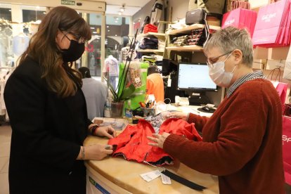 Una comerciante y una clienta en Lleida con mascarilla, obligatoria en interiores.