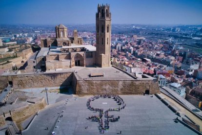 Amb cartells liles desenes de persones van formar el símbol feminista a la capital del Segrià. A la dreta, la xarrada celebrada al parc de Serrallarga.