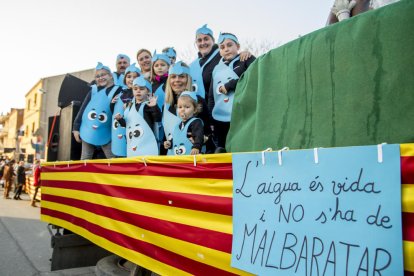 Una carrossa de la desfilada de la festa amb nens vestits de gotes d'aigua que demanen no malgastar-la.