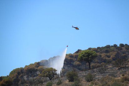 Un helicóptero descarga agua sobre uno de los focos registrados en Portbou.