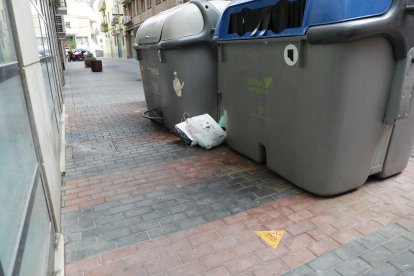 Bolsas fuera del contenedor, y la pegatina que avisa de las multas por esta actitud incívica.