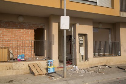 Una entrada al edificio sin puerta, con instalaciones eléctricas rotas y una tapia perforada.