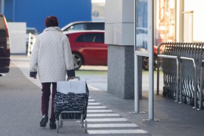 Una dona surt d’un supermercat amb el carret d’anar a comprar.