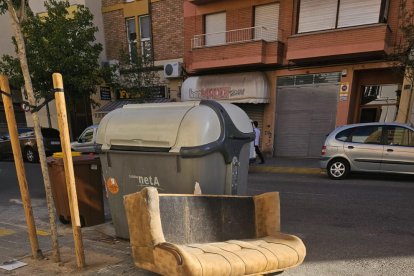 Un sofá tirado a lado de un contenedor en la calle Centre. 